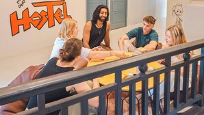 A group of people seated around a table in a room with a sign reading "KIA Hotel". - KITA Hostel (George Town)