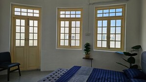 A room with a bed, a chair, and three windows. - KITA Hostel (George Town)