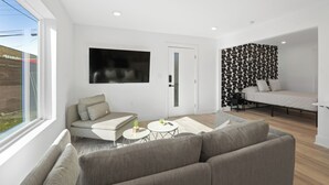 Ein modernes Wohnzimmer mit einer Couch, einem Couchtisch und einem an der Wand befestigten Fernseher.