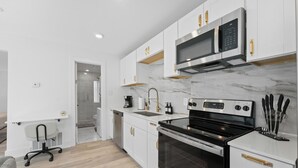 A modern kitchen with white cabinetry, stainless steel appliances, and a marble backsplash. - Cozy Studio in Downtown Dallas Lower Greenville (Dallas)