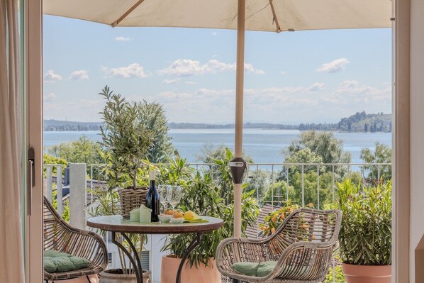Un balcon avec des fauteuils en osier, une table avec une bouteille et des verres, et des plantes en pot.