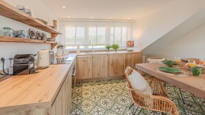 Eine Küche mit Holzschränken, einer Frühstückstheke und einem Essbereich mit Korbstühlen.