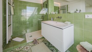 Ein Badezimmer mit grünen Fliesen, einem weißen Waschbecken, einem Spiegel und einem Handtuchhalter.