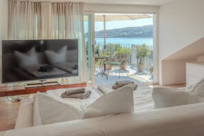Ein Schlafzimmer mit Fernseher, ein Balkon mit Tisch und Stühlen sowie Meerblick.