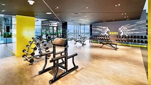 Ett modernt gym med olika typer av träningsutrustning, en vägg med ordet ”SPRINT!” och hantlar.