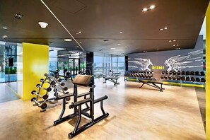 Un gimnasio moderno con varios equipos de ejercicio, una pared con la palabra 'RUN!' y mancuernas.