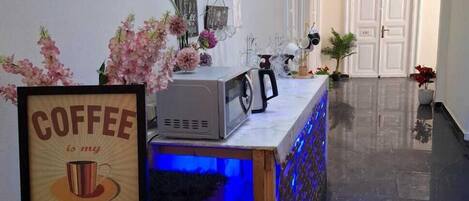 A reception area with a coffee station, framed sign, decorative flowers, and a polished floor.