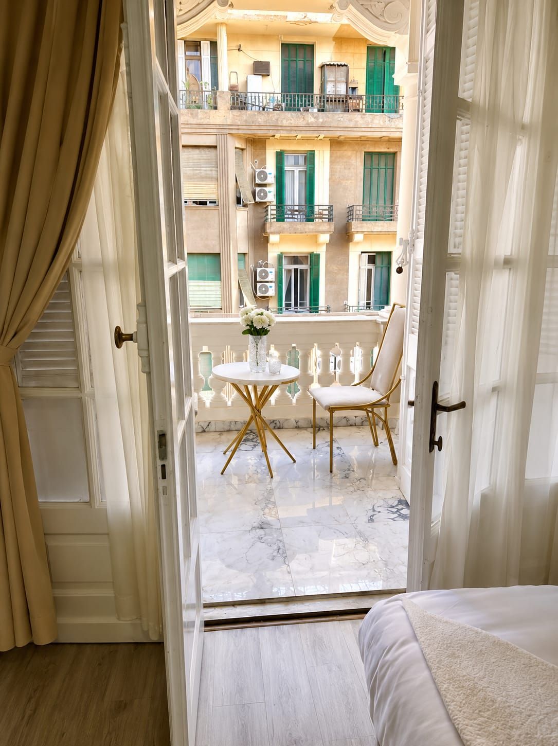 A hotel room with a balcony, a bed, and a small table with chairs.