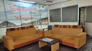 A hotel lobby with two sofas and a coffee table, a large welcome sign, and a view of a mountainous landscape. - SRI SUBHAMASTHU GRAND (Vijayawada)