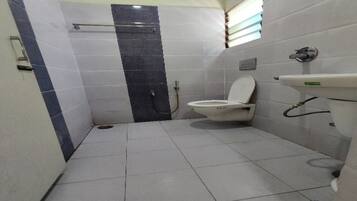 A small bathroom with a toilet, a sink, and a shower area.