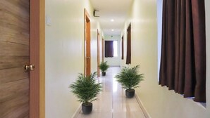 A hallway with wooden doors, potted plants, and a view into another room. - SRI SUBHAMASTHU GRAND (Vijayawada)