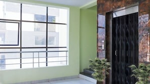 A room with a large window, a door with a metal frame, and two potted plants. - SRI SUBHAMASTHU GRAND (Vijayawada)