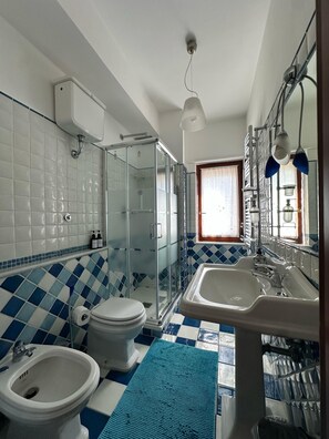 A bathroom with a glass-enclosed shower, a toilet, a bidet, and a sink with a mirror. - Ketty's House Apartment between sea and mountains (Vico Equense)