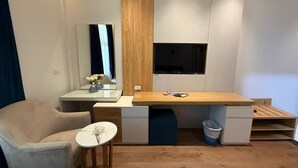 Una habitación compacta con un escritorio de madera, una silla, una mesita y un espejo.