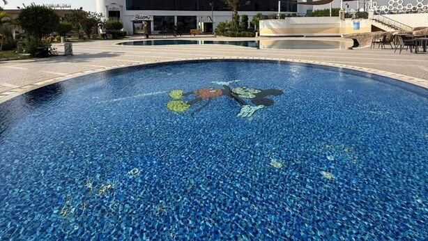 Una piscina con un edificio moderno al fondo.