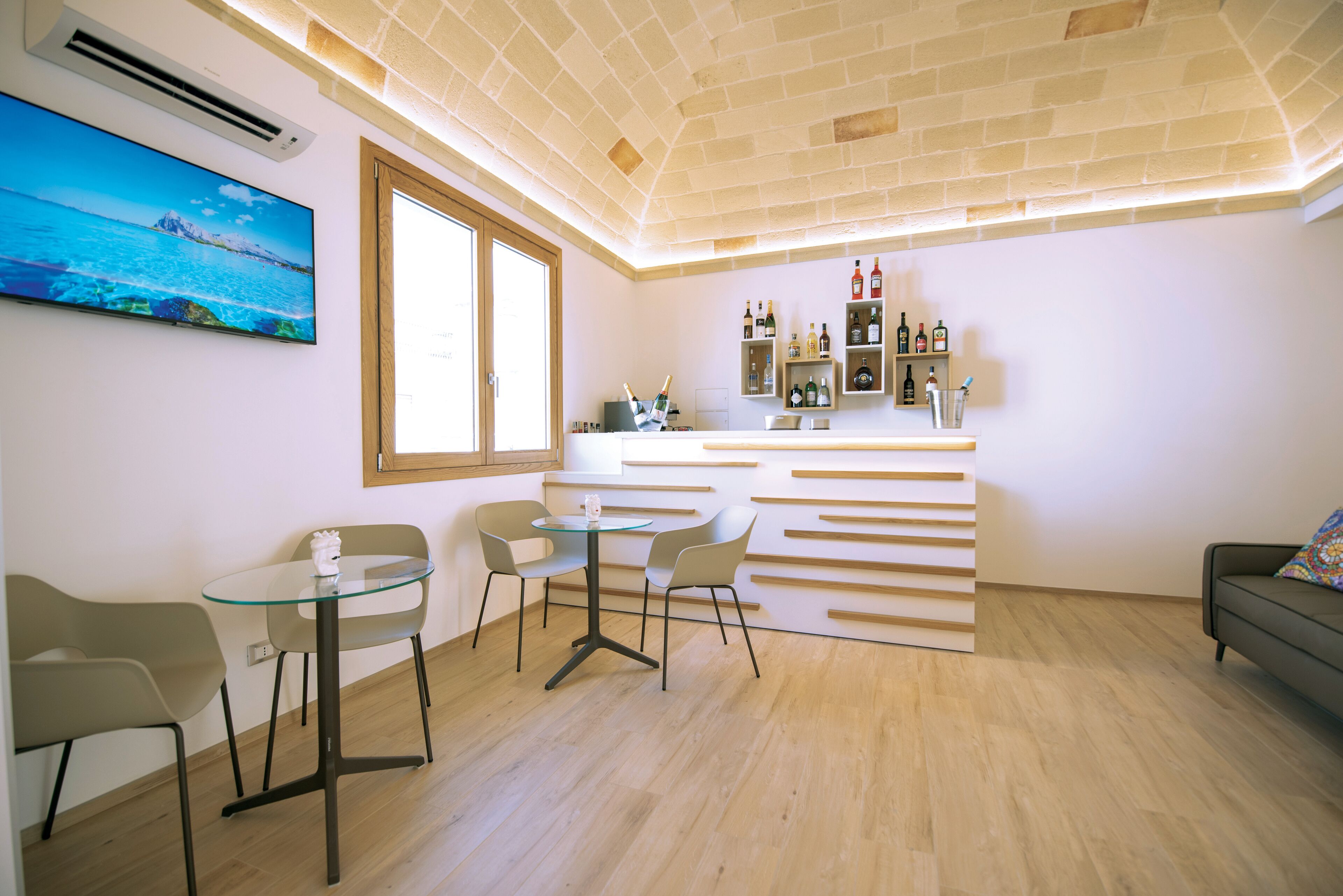Una cocina moderna con barra integrada, piso de madera y un ventanal grande.