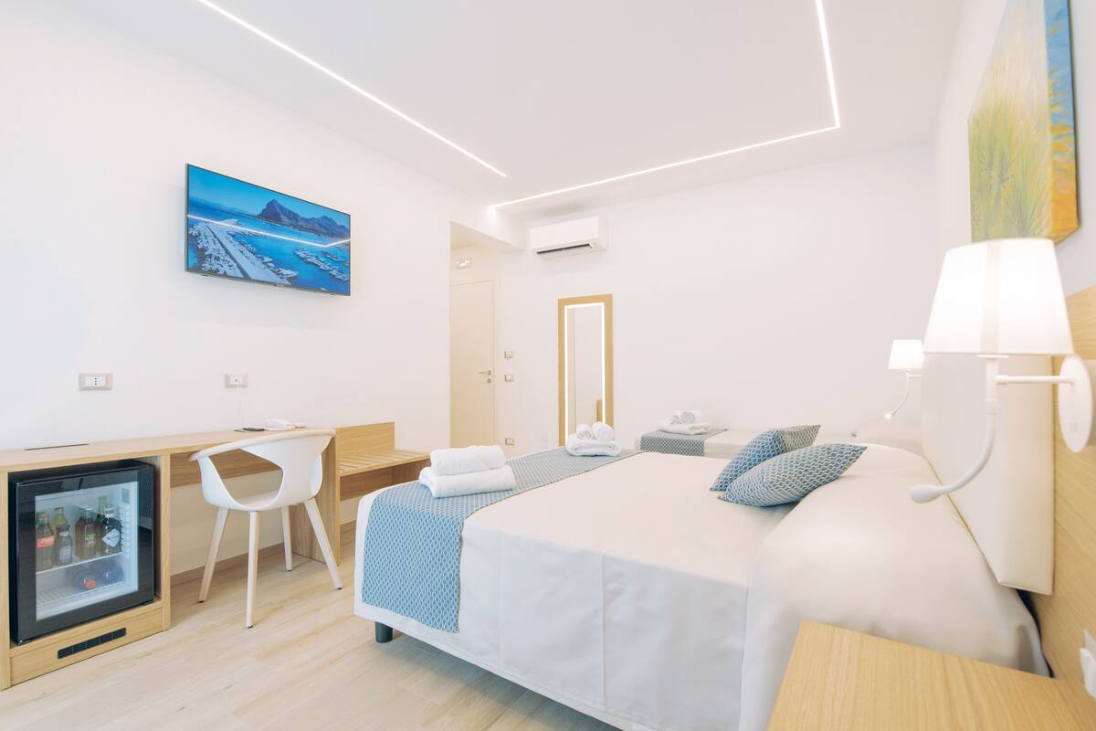 Una habitación de hotel moderna con cama, escritorio, silla y refrigerador.