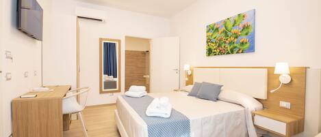 Ein modernes Hotelzimmer mit Bett, Nachttischen, Schreibtisch und Fernseher.