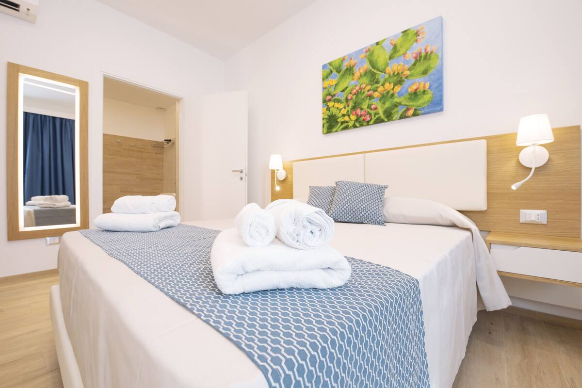 Habitación de hotel con dos camas, ducha, un cuadro en la pared y un espejo.