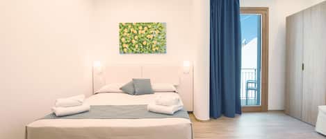 A modern bedroom with a large bed, a painting on the wall, and a view of the outdoors through a window.