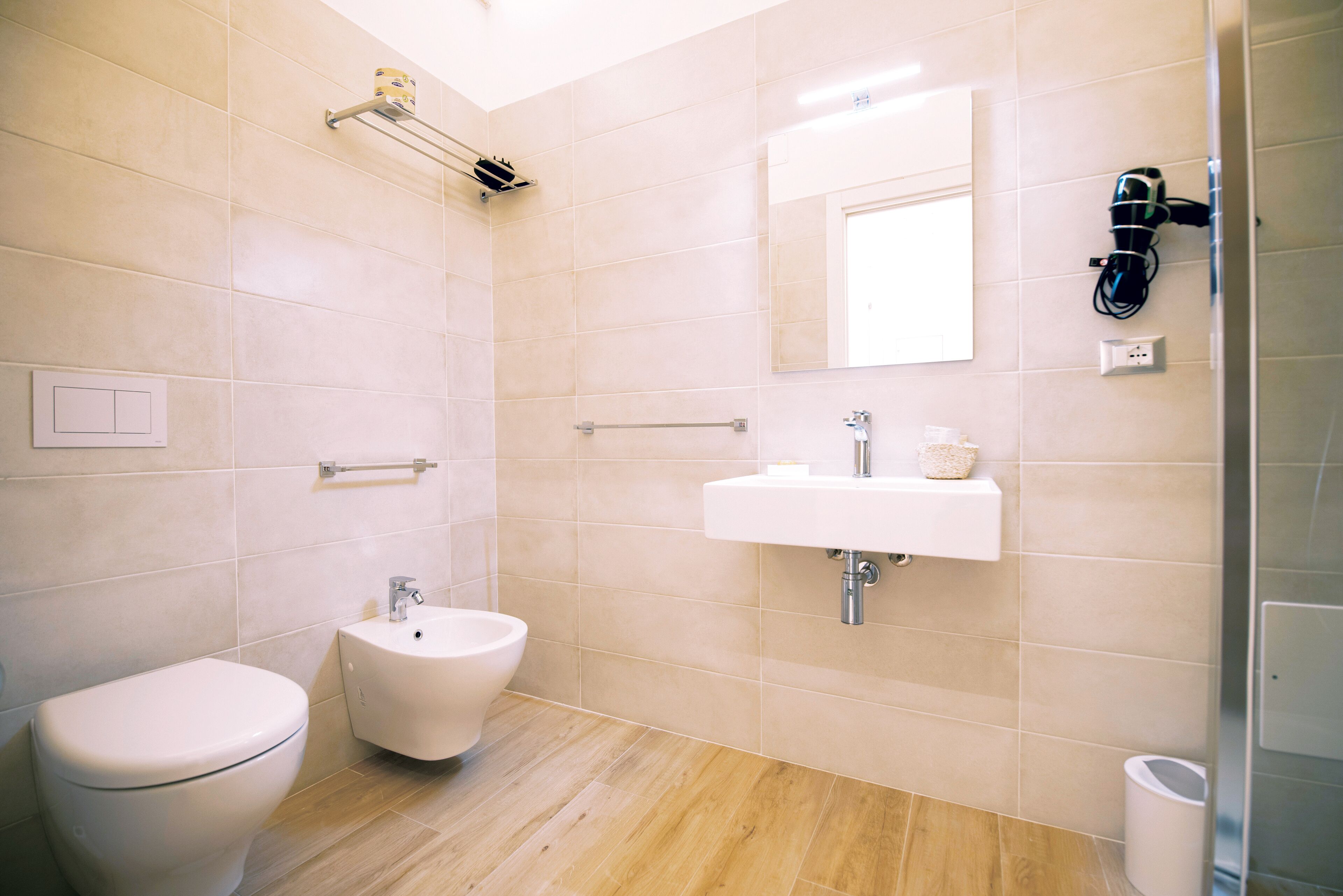 A modern bathroom with a toilet, bidet, sink, and a mirror.