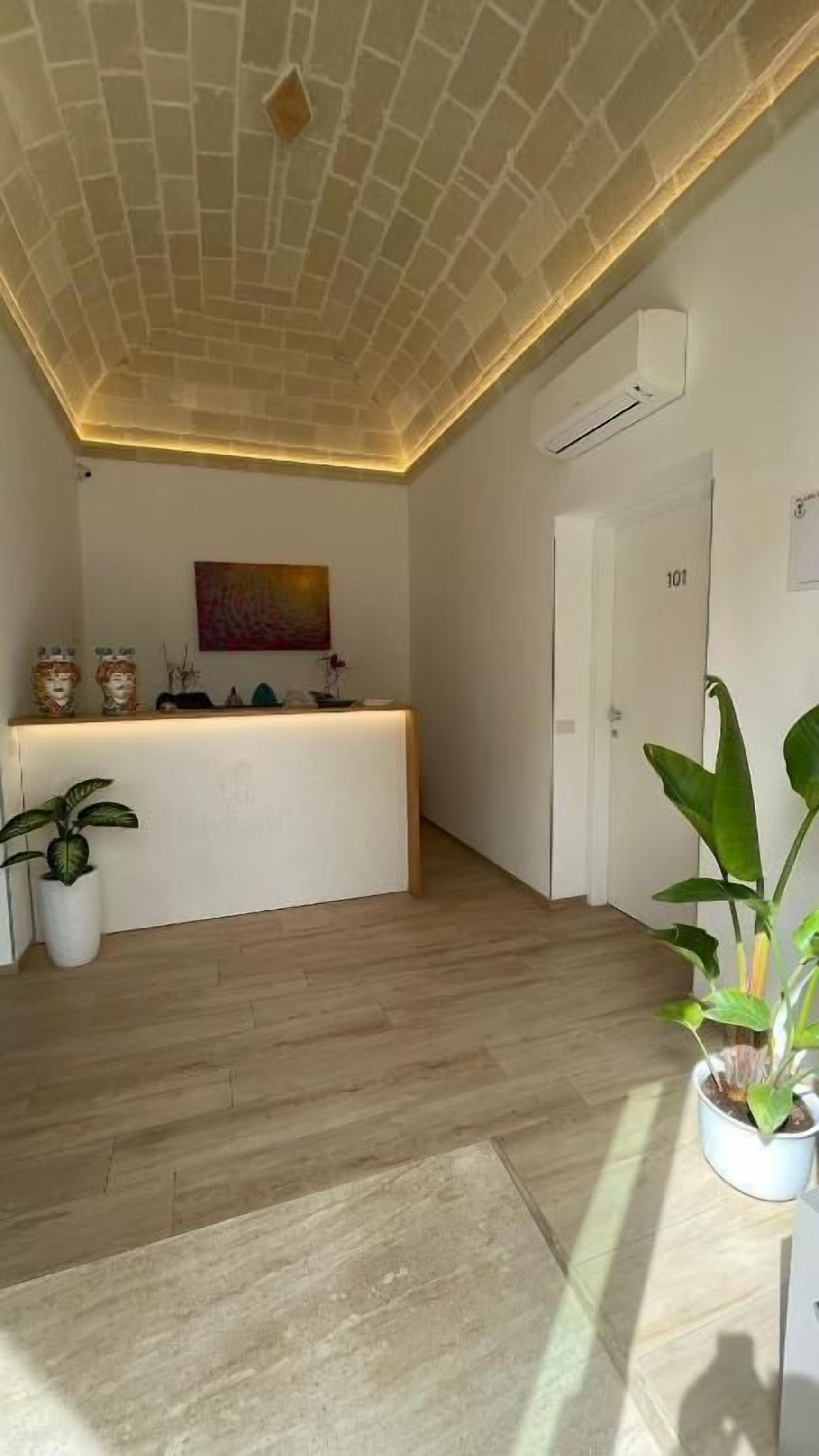 A reception area with a wooden floor, a reception desk, and a ceiling with a brick pattern.