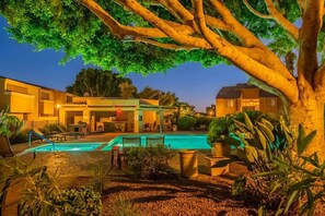 Un área de piscina con un sillón de descanso, una piscina pequeña y un edificio con un letrero que dice "Lounge".