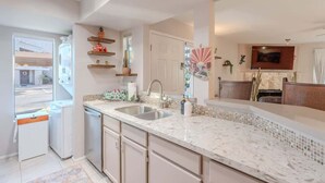 A modern kitchen with a marble countertop, stainless steel sink, and built-in cabinets. - Starlight Escape - Heated Pool & Spa by Old Town! (Scottsdale)