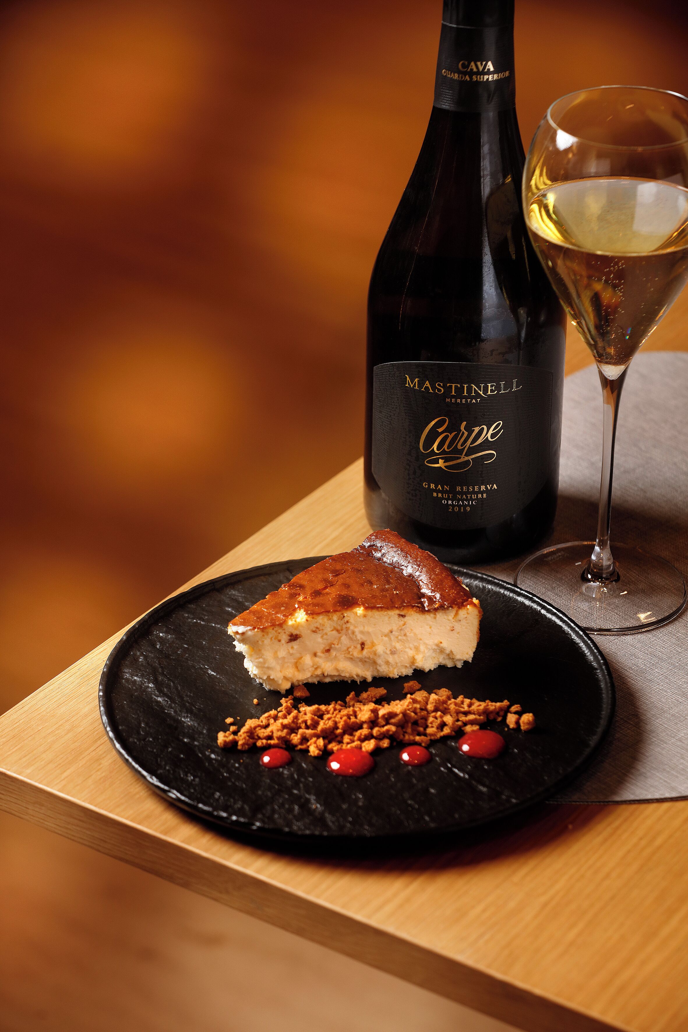 A bottle of wine, a glass, and a slice of cake on a plate.