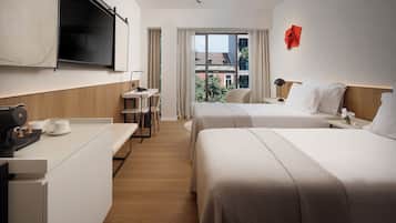 A hotel room with a bed, bedside table, TV, and a desk with a chair.