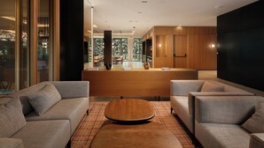Un interior moderno con sofás, una mesa baja de madera y una zona de cocina con armarios de madera.