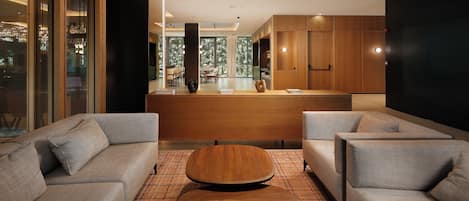 A modern interior with sofas, a wooden coffee table, and a kitchen area with wooden cabinets.