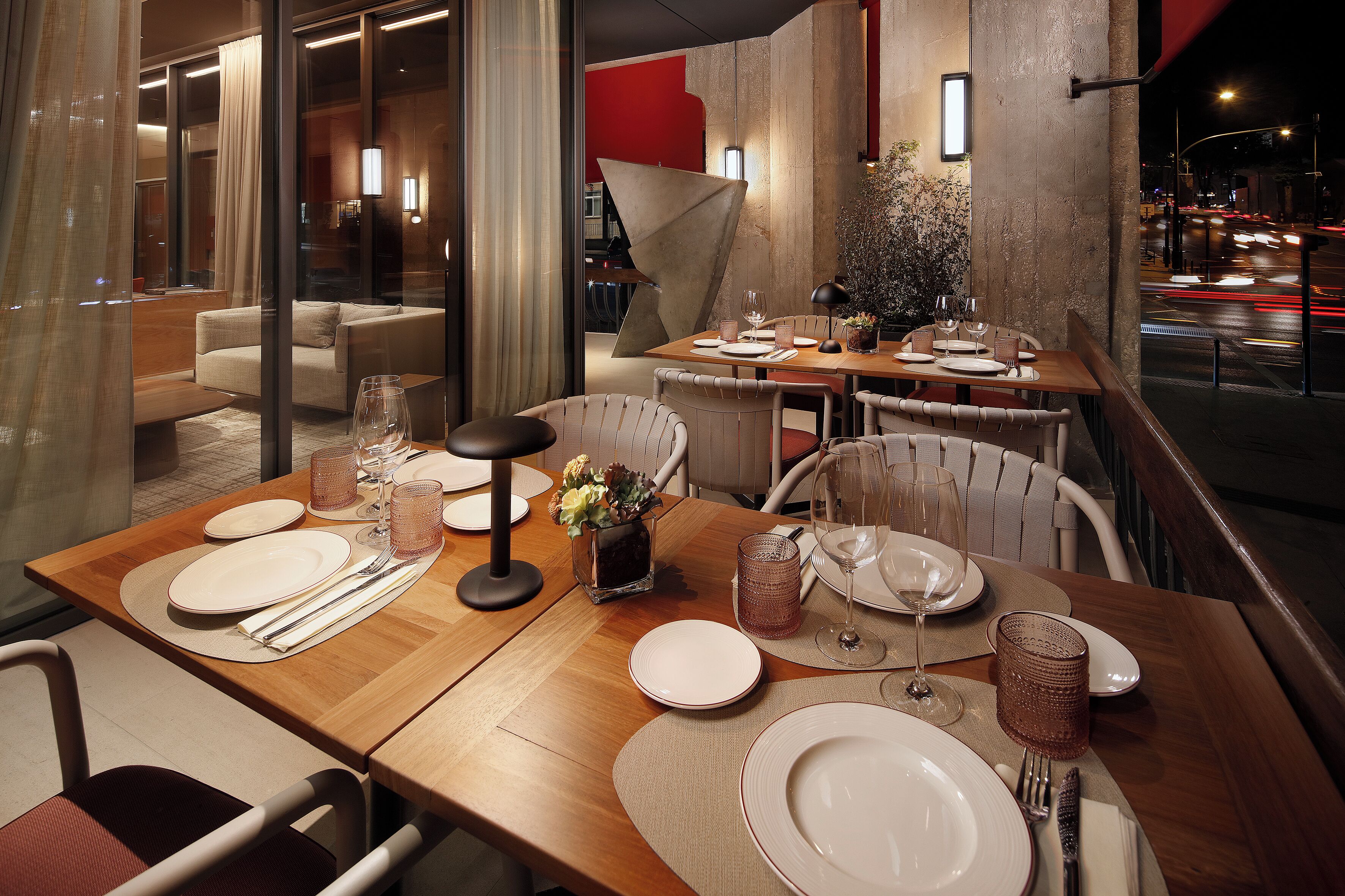 A restaurant with tables set for dining, a modern interior, and a view of the street.