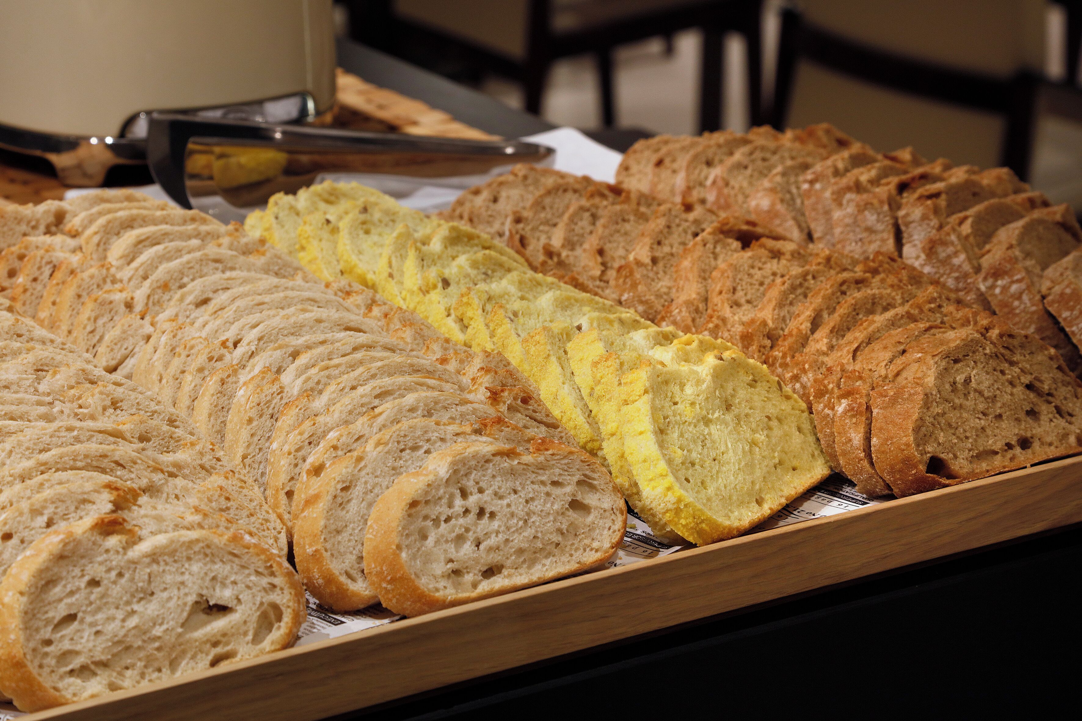 A variety of sliced breads on a wooden tray.