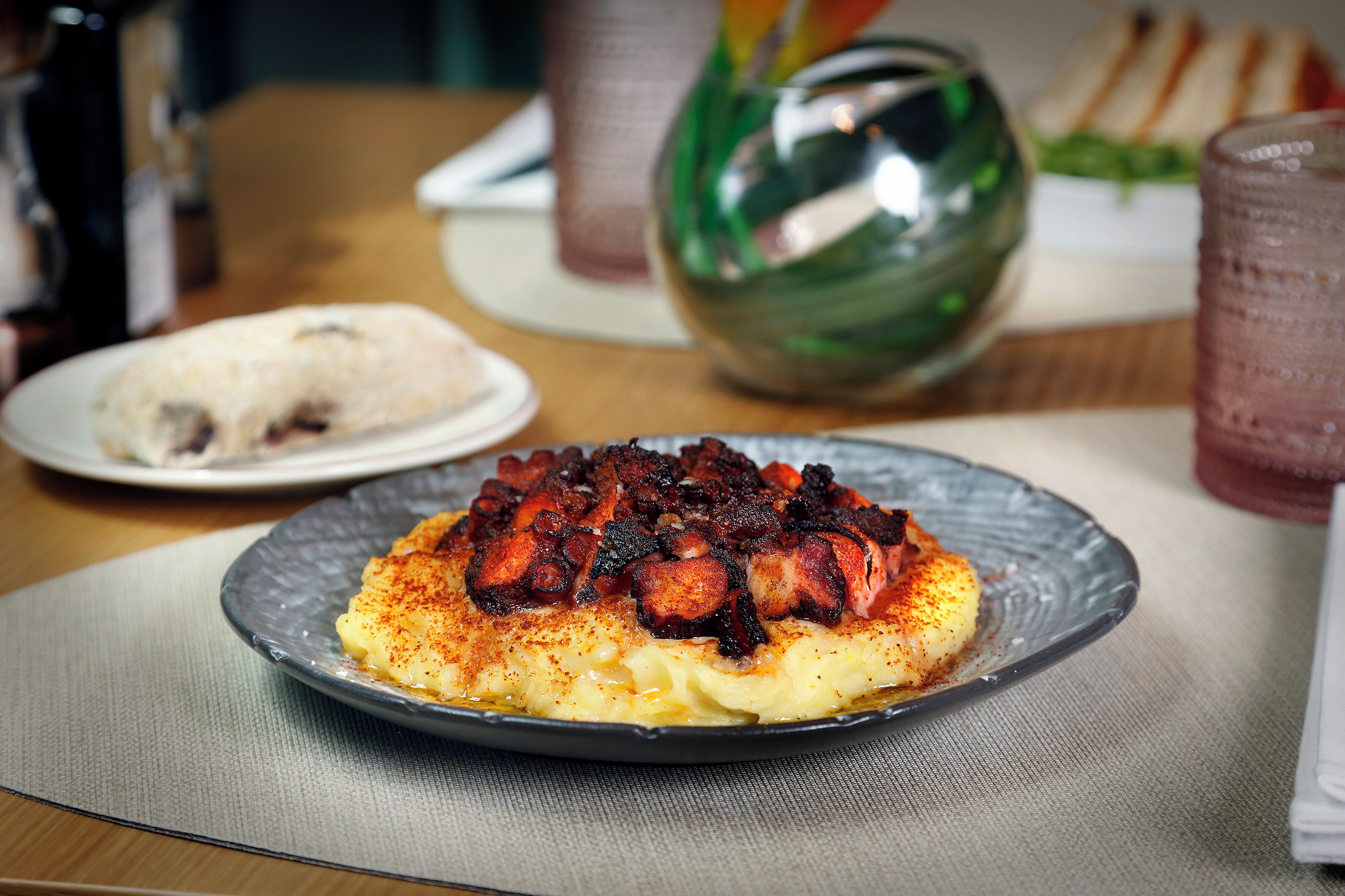 Un plat de menjar amb una base cremosa i una cobertura que sembla carn a la planxa, possiblement pop.