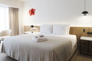 Ένα δωμάτιο ξενοδοχείου με ένα κρεβάτι, μια καρέκλα, ένα γραφείο και ένα φωτιστικό.