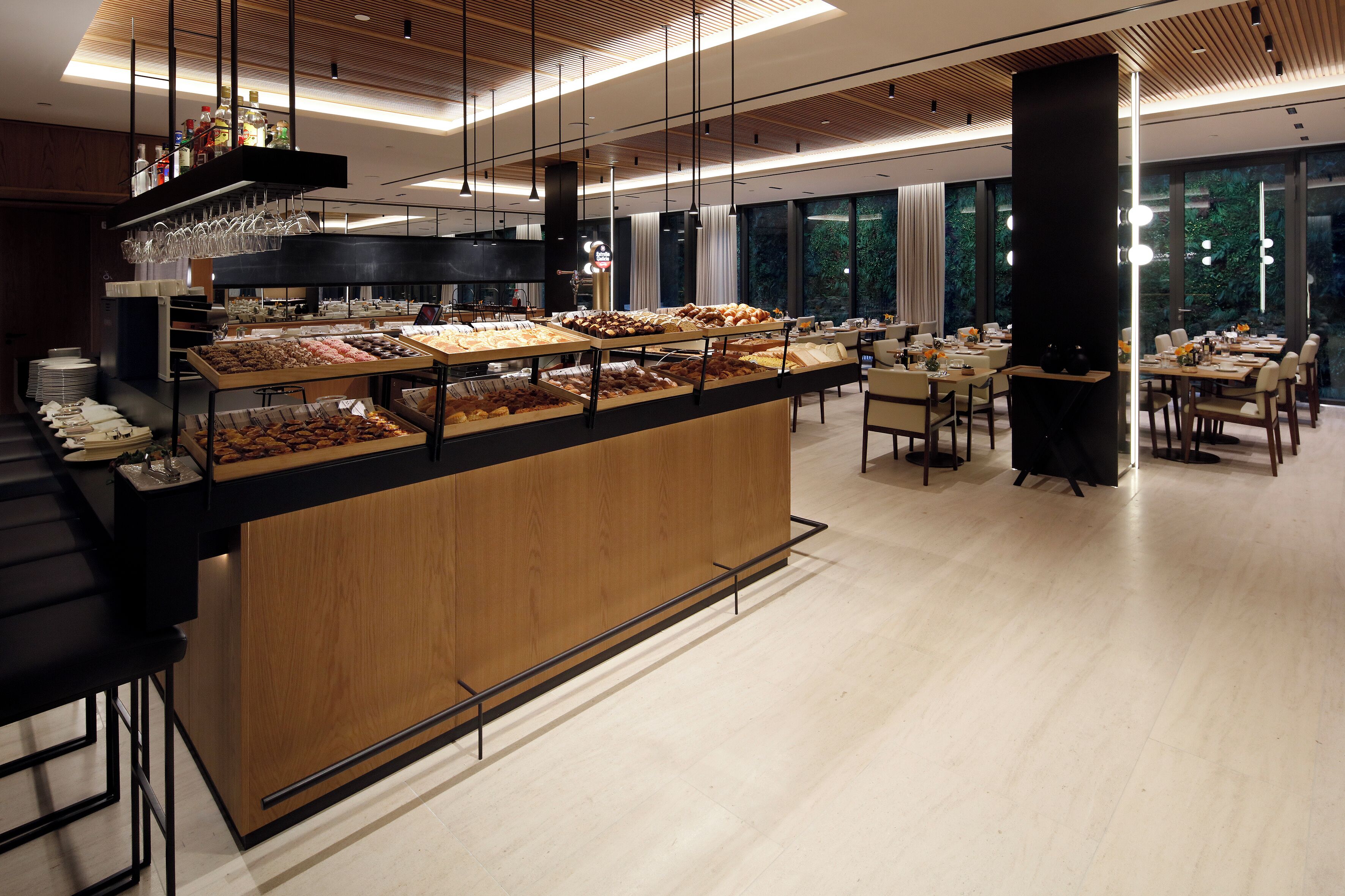 A modern restaurant with a central counter displaying various food items, surrounded by dining tables and chairs.