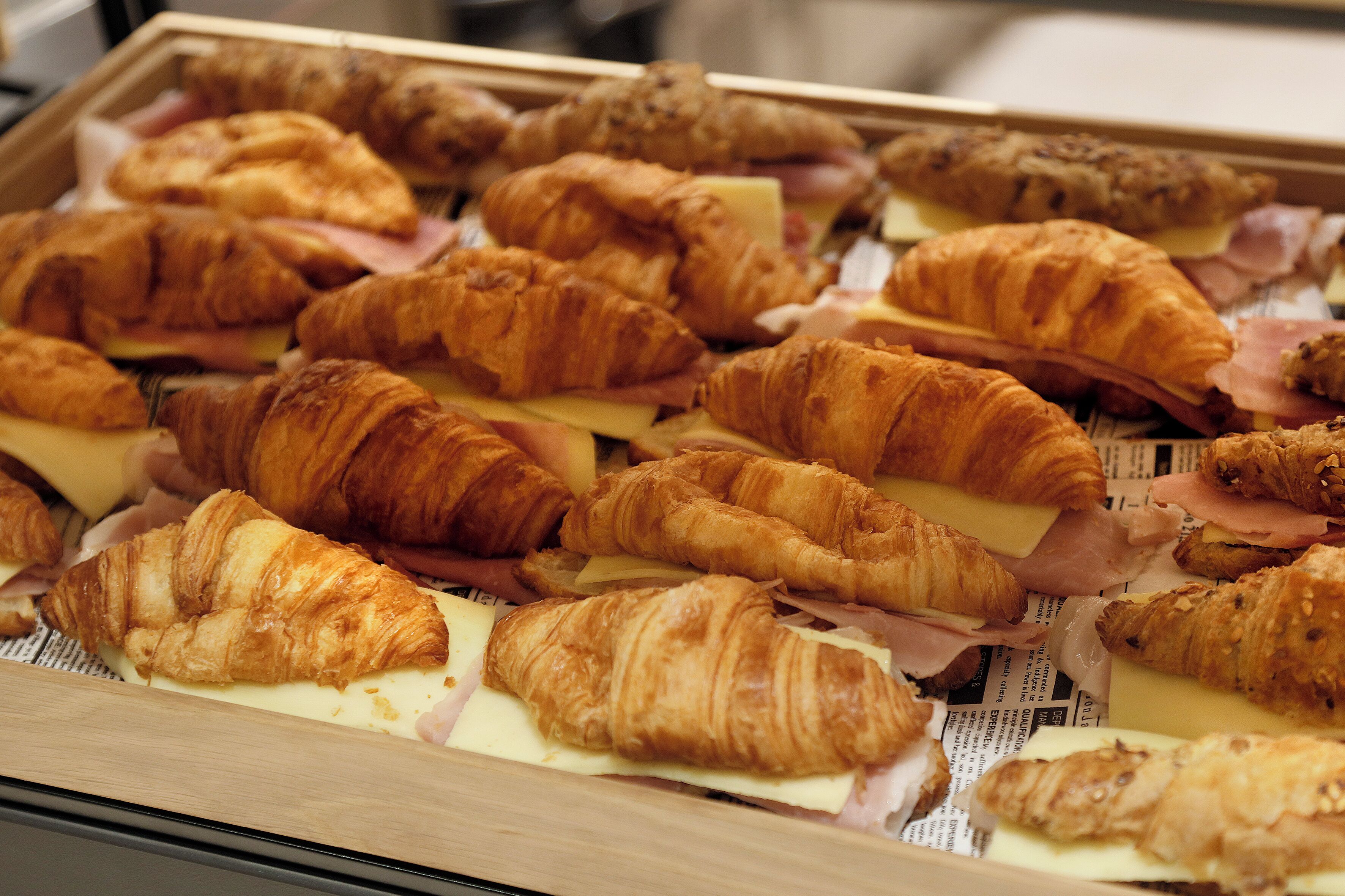 Une variété de viennoiseries et de sandwichs, notamment des croissants, présentés sur un plateau.
