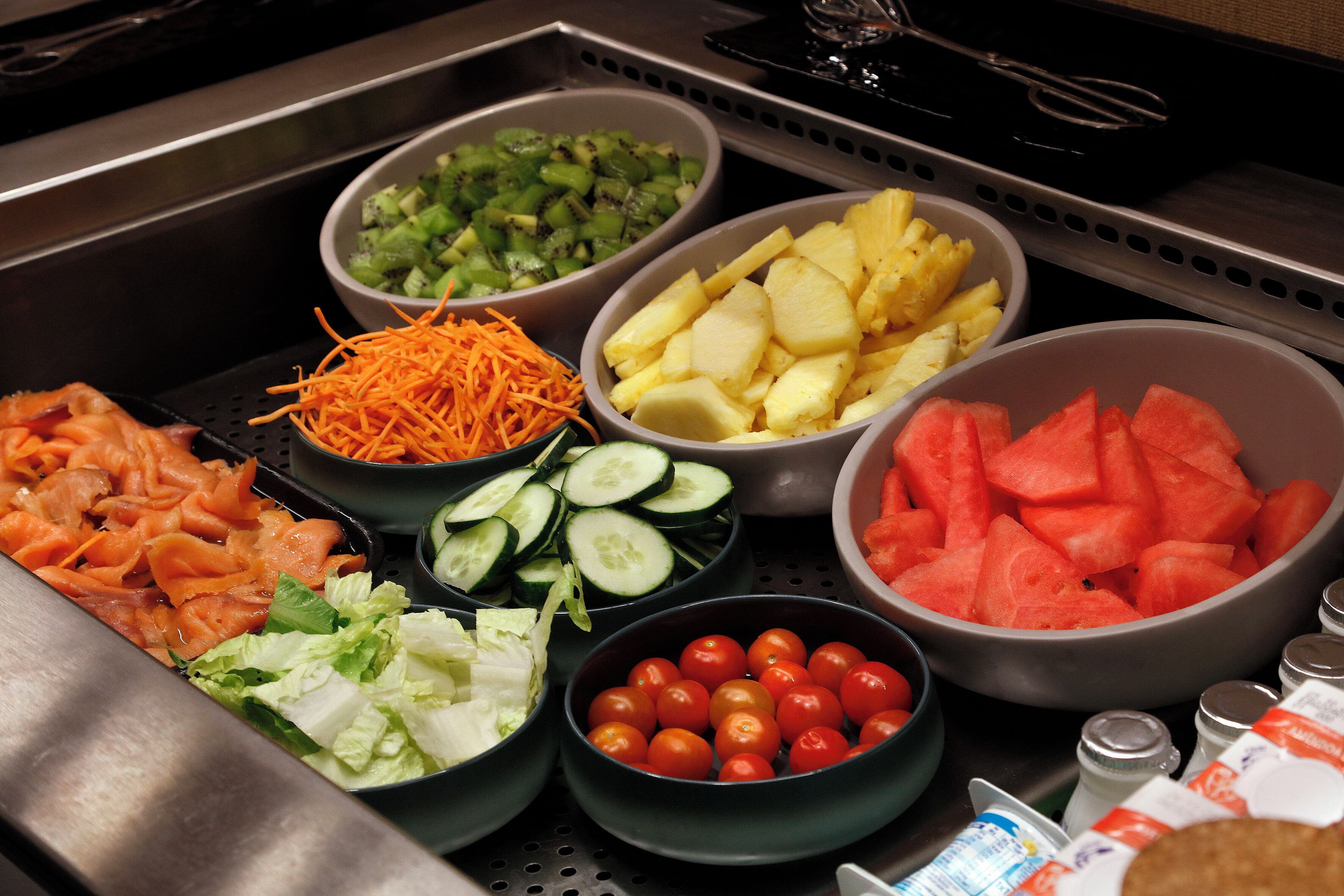Un bufé con diversos alimentos, incluyendo verduras, frutas y carnes.