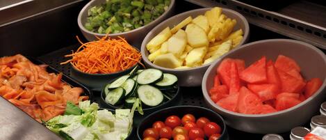 Un bufé con diversos alimentos, incluyendo verduras, frutas y carnes.