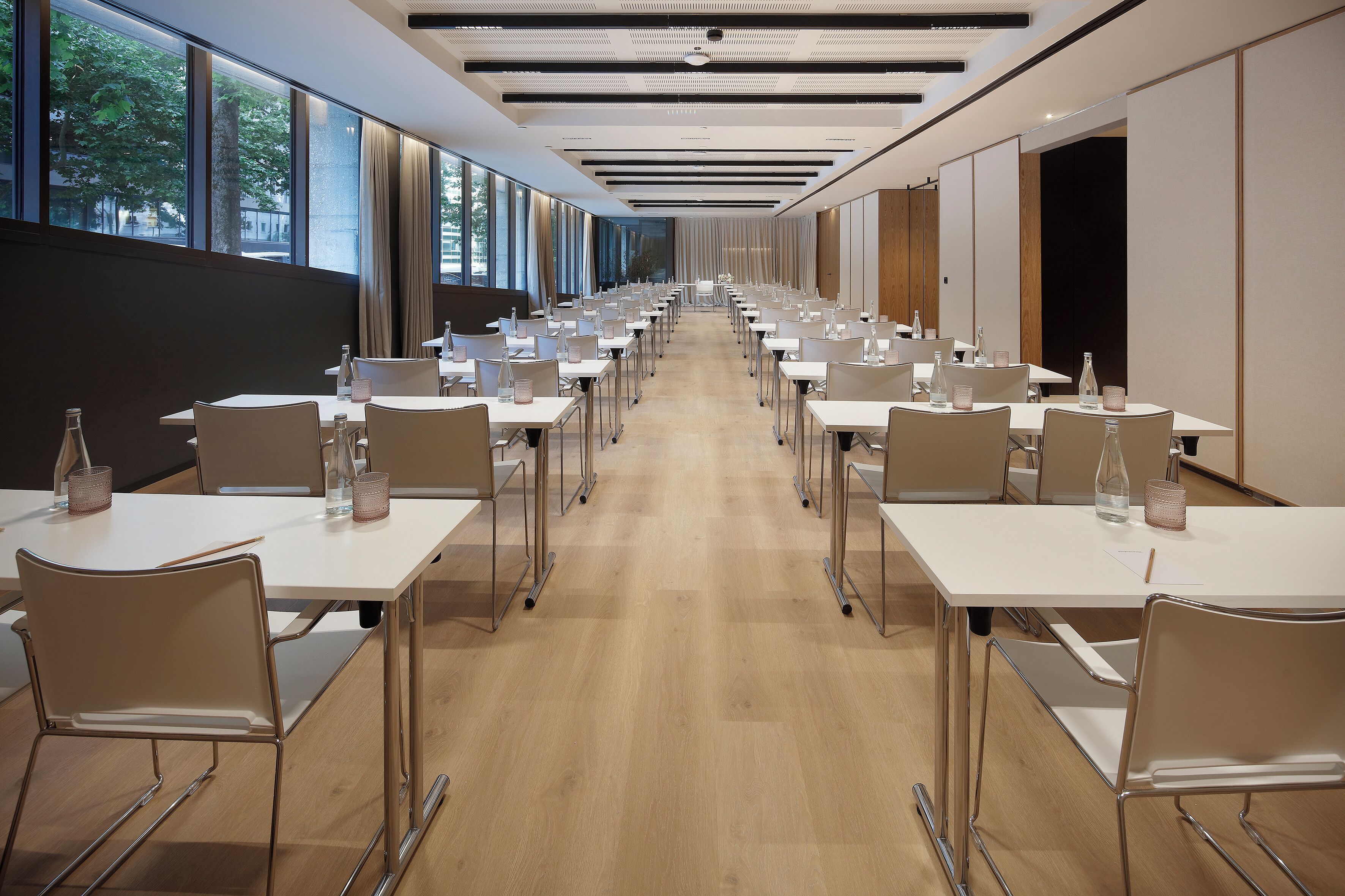 A conference room with tables, chairs, and large windows.