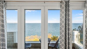 A balcony with a view of the sea, featuring a table and chairs. - Amazing Water views! Ocean front, HotTub & More! (Plymouth)