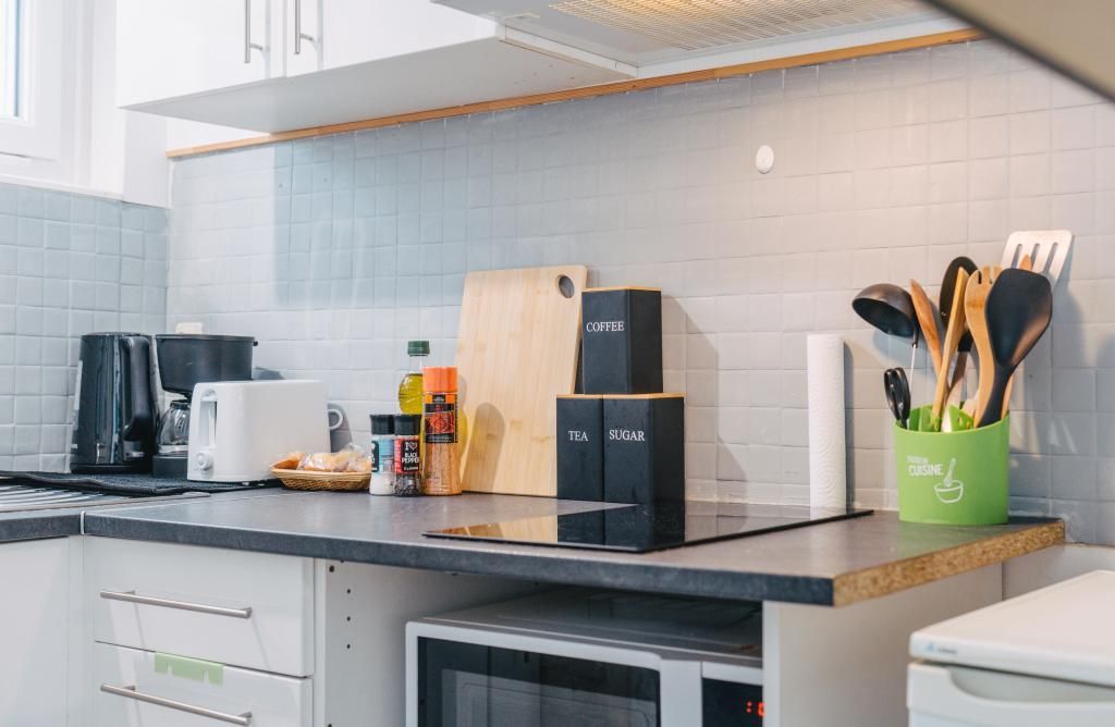 Une cuisine équipée d’une machine à café, de boîtes à thé et à sucre, d’une planche à découper et d’un porte-ustensiles.