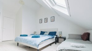 Een slaapkamer met dakraam, twee bedden en een witte deur.