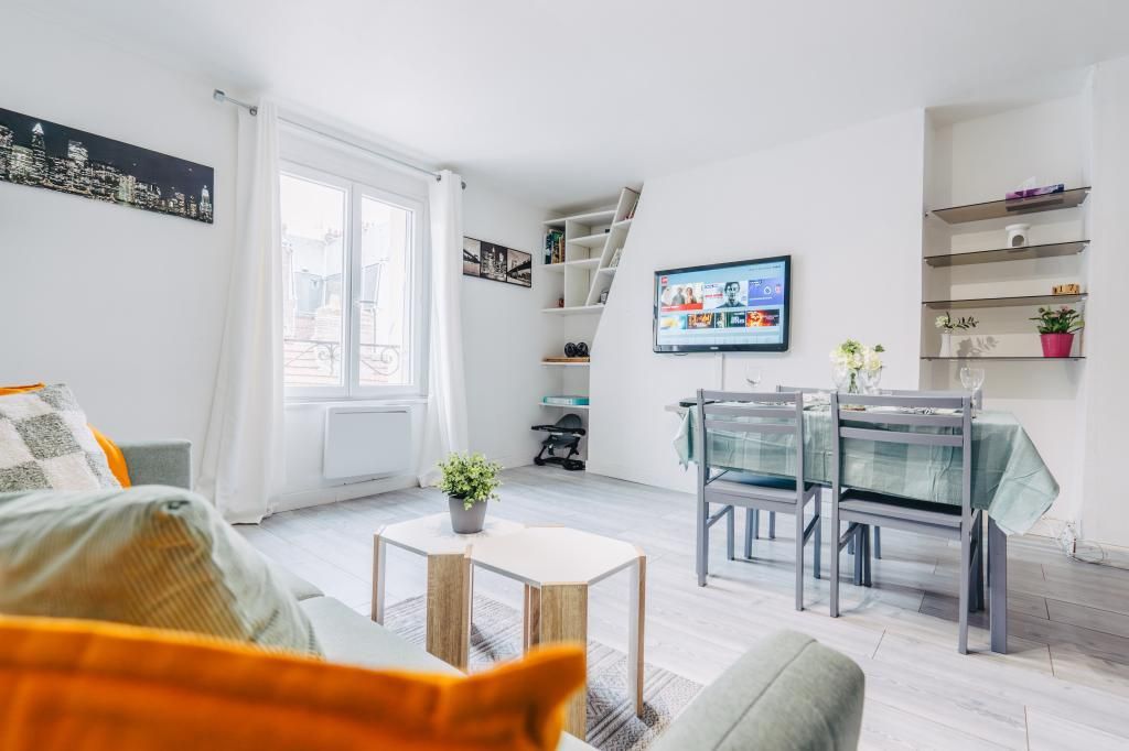 Un salon moderne avec un canapé, une table à manger et des chaises, un téléviseur et une vue sur la ville.