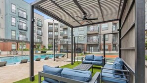 Un espace extérieur aménagé, abrité et doté de bancs bleus rembourrés, d’une piscine et d’une vue sur des immeubles d’habitation.