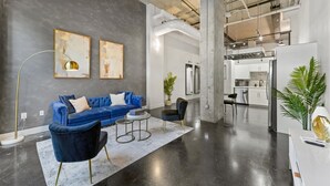 A modern living area with a blue sofa, black chairs, and artwork on the wall. - Stylish Loft Deep Ellum Dallas Tx (Dallas)