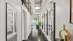 A hallway with mirrored walls, a black floor, and a decorative vase on a console table. - Stylish Loft Deep Ellum Dallas Tx (Dallas)