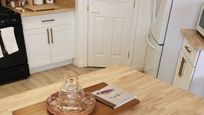 A kitchen with a wooden table, two white cushioned chairs, a book, and a glass container on the table. - Near ​JT Park: Hot Tub, Cinema, Arcade Game, GameRM  (Yucca Valley)