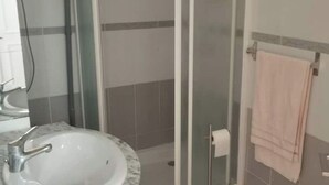 A bathroom with a sink, a glass shower enclosure, and a towel rack.